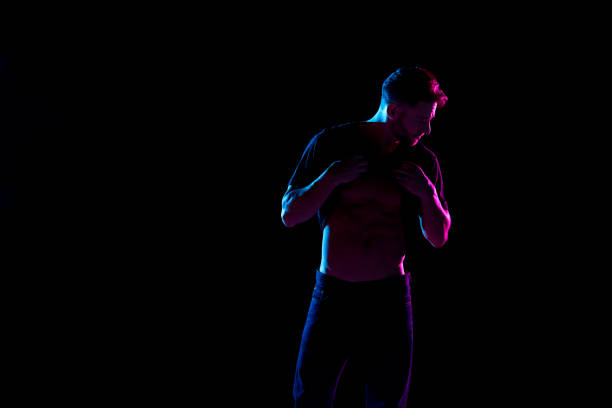 istock Handsome man with black shirt with colored gel lighting 1139396471
