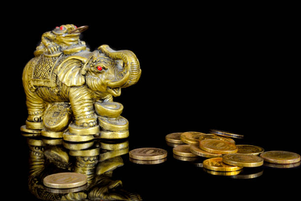 The Chinese symbol of wealth - an elephant with a toad and coins on a black background with reflection. The Chinese symbol of wealth - an elephant with a toad and coins on a black background with reflection. The isolated objects on a black background. Indoors. Horizontal format. Color. Photo. elephant figurine stock pictures, royalty-free photos & images