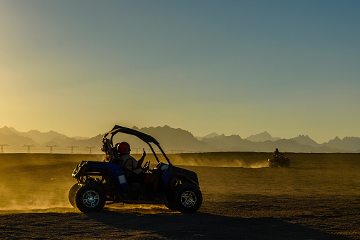 Unrecognizable people driving buggy during safari trip at sunset in Arabian desert not far from Hurghada city, Egypt
