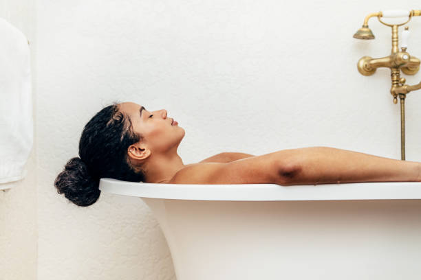 vue latérale de la jeune femme ayant un bain - prendre un bain photos et images de collection