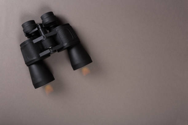 istock Black binoculars with orange lens on pastel background 1139421604