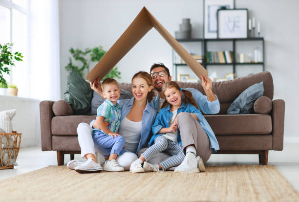 concept of housing and relocation. happy family mother father and kids with roof at home concept of housing and relocation. happy family mother father and kids with roof at a  home family home stock pictures, royalty-free photos & images