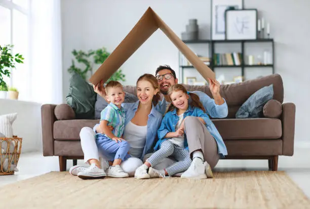 Photo of concept of housing and relocation. happy family mother father and kids with roof at home