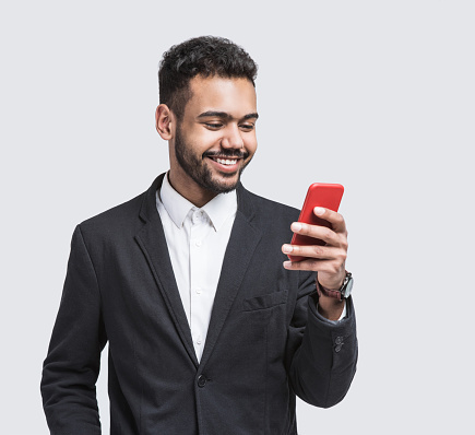 Cheerful young men holding smart phone. Isolated on gray background