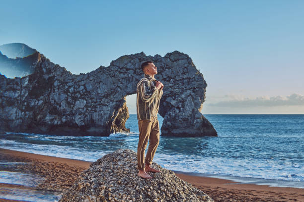 istock Young Man Standing On Rock At Beach 1139426469