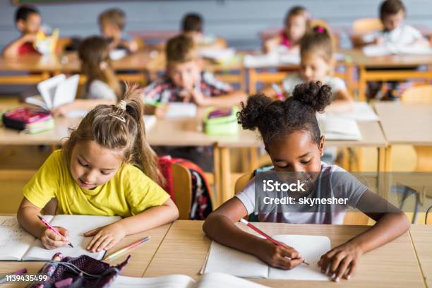 Happy Schoolgirls Writing A Dictation On A Class At School Stock Photo - Download Image Now