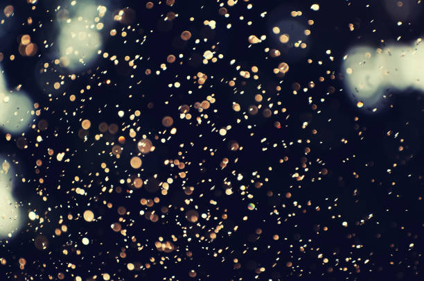 istock Defocused bokeh blurred golden lights from a falling rain over a dark natural background. Great for creative projects and various designs. Cross process. 1139436425