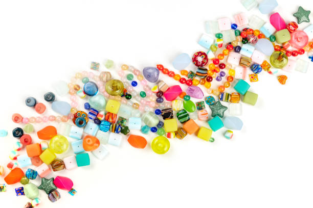 ein overhead-foto von vielen verschiedenen perlen, von oben auf weißem hintergrund mit einem platz für text aufgenommen - bead glass jewelry stone stock-fotos und bilder