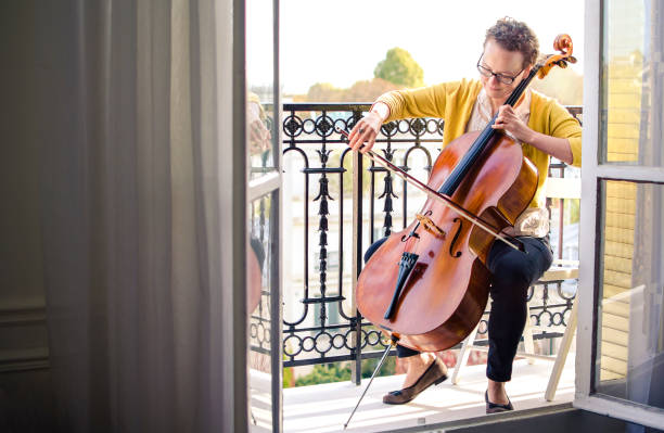 musicista classica femminile che suona il violoncello su un balcone a parigi - musica classica orchestrale foto e immagini stock
