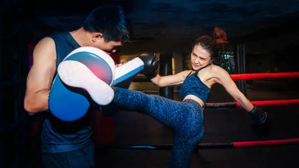 Girl doing kick exercise during kickboxing training with personal trainer