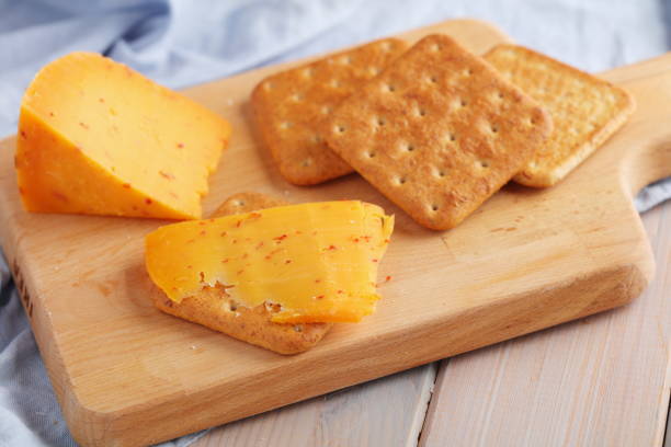 Crackers with spiced gouda cheese and a slice of cheese on a wooden board