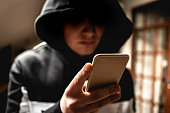 male hacker in the hood using a mobile phone, stealing your personal data f