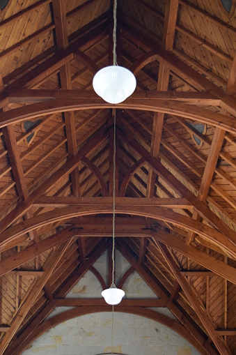 Timber beams and arches of an old church building roof structure forming an interesting symmetrical pattern.