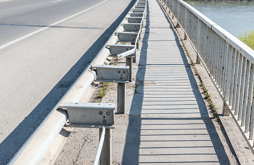 Damaged and broken security metal or iron fence on the bridge construction from car crash or traffic accident