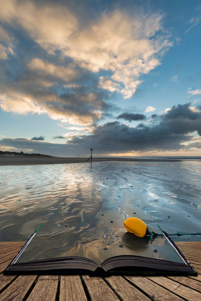 superbe lever de soleil d’hiver sur la plage de west wittering dans le sussex en angleterre avec le vent soufflant le sable à travers la plage dans des pages de livre ouvert, concept de narration d’histoire - witterung photos et images de collection