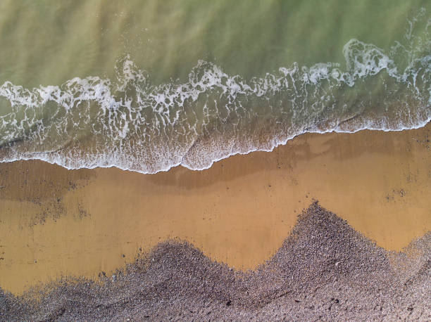 istock Bird's eye top down view of small waves lapping onto bach with sand and shingle creating textured layers in the landscape 1139455713