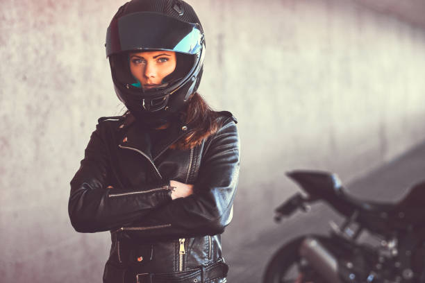 Close-up portrait of a biker girl with her arms crossed next to her superbike inside the bridge. stock photo