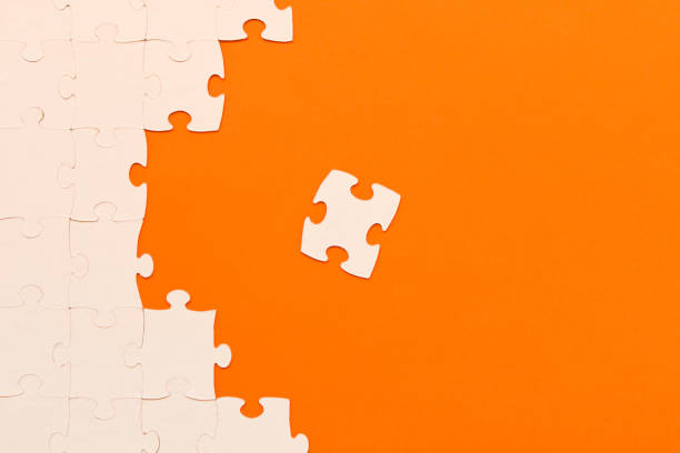 istock White jigsaw puzzles on orange background. The concept of development of thinking. 1139457544