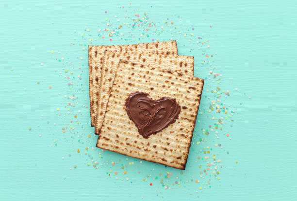 concetto di celebrazione pesah (festa ebraica di pasqua) con cuore di cioccolato sopra il matzah. lay piatto con vista dall'alto - matzo table blue horizontal foto e immagini stock