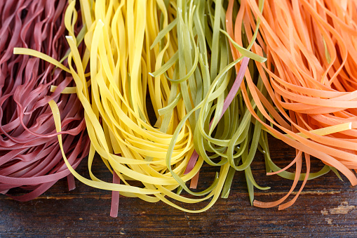 raw multicolored italian spaghetti on the table. space for text