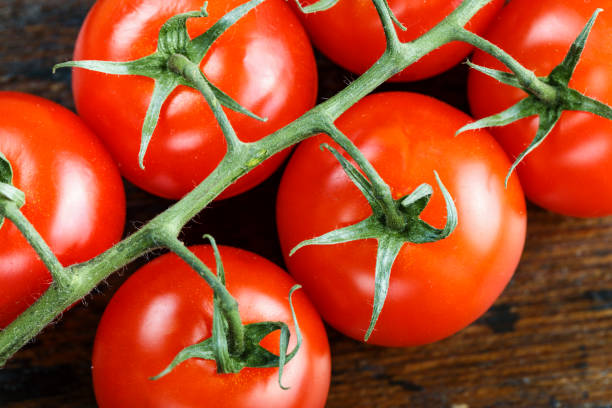 istock Ripe cherry tomatoes on a twig lie on a brown wooden table. 1139458121