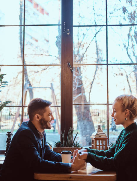 istock Attractive young couple holding hands, looking at each other and talking while sitting in the restaurant. 1139459330