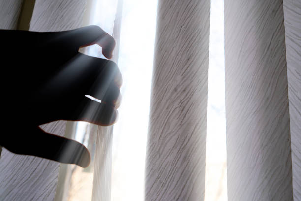 istock hand opens jalousie with the light sun ray going through it 1139459486