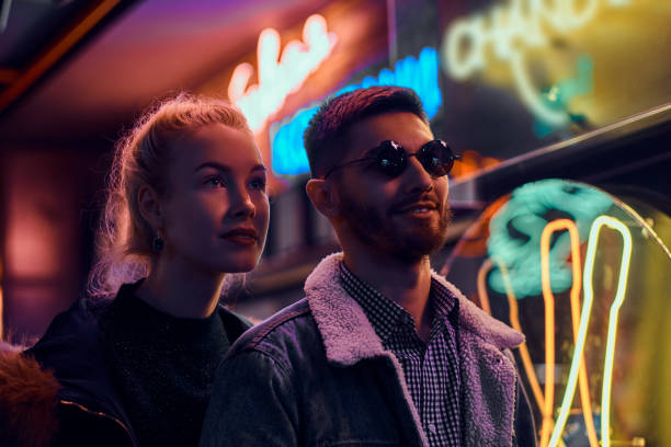 une belle fille et bel homme debout dans la nuit dans la rue. - neon light disco lights illuminated nightlife photos et images de collection