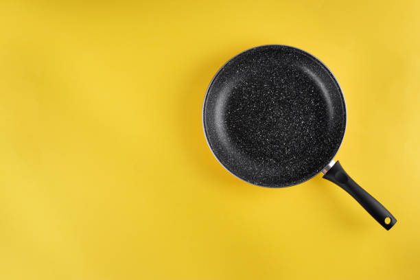 padella vuota in ghisa su sfondo giallo. - cast iron skillet foto e immagini stock