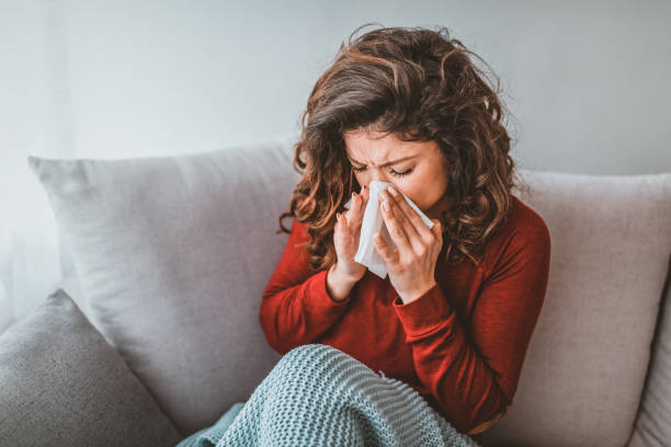 portrait of woman with allergy blowing her nose - cold imagens e fotografias de stock