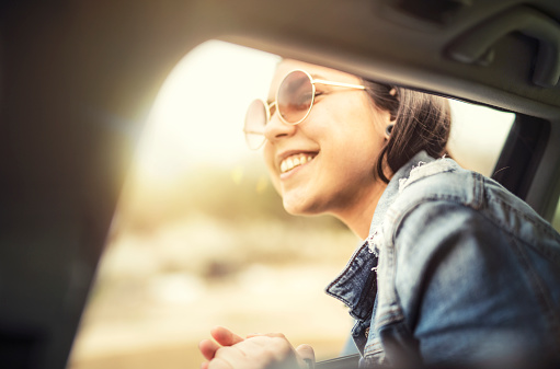 Latino Woman with sunglasses on a road trip with car