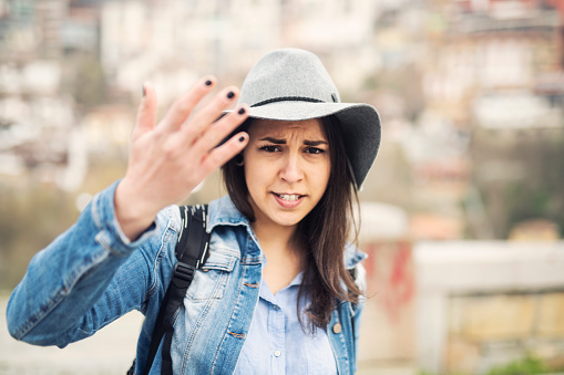 A Latino woman with a negative face does not want to be shot with stop gesture