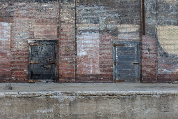 istock Two large metal doors attached to an abandoned crumbling red brick warehouse 1139466807