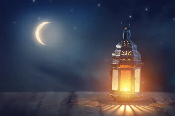 Ornamental Arabic lantern with burning candle glowing at night. Festive greeting card, invitation for Muslim holy month Ramadan Kareem."n