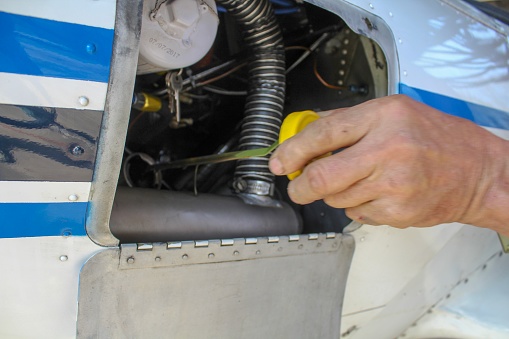 Closeup of Man checking oil in engine of Vintage Airplane