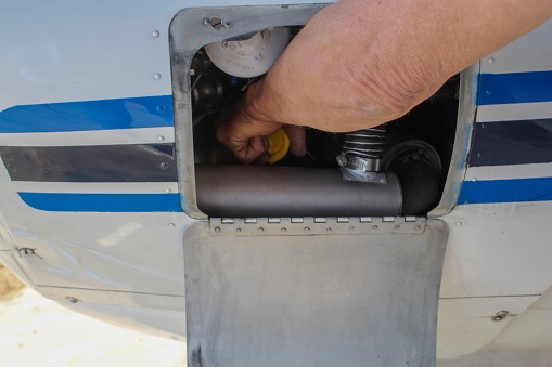 Man's Hand reaching into airplane engine to check oil