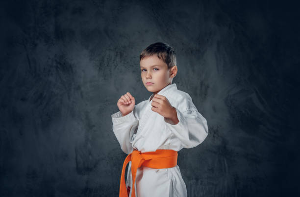 Preschooler boy dressed in a white karate kimono with orange belt.