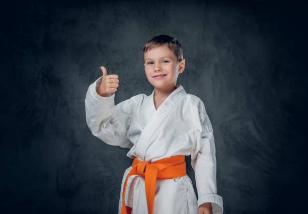 menino de preschooler vestido em um quimono branco do karaté. - karate child judo belt - fotografias e filmes do acervo