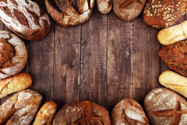 istock Different kinds of bread and bread rolls on board from above. Kitchen or bakery 1139477182