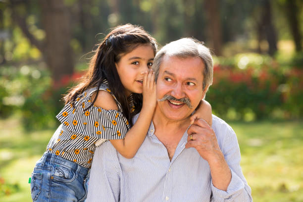 nonno e nipote che giocano in giardino - whispering grandparent child grandfather foto e immagini stock