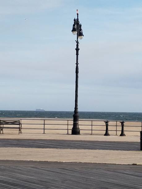 istock Lampost on the beach boardwalk and distant ship 1139487150