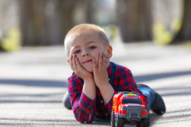 istock blonde toddler boy playing outdoors lying at street 1139488051