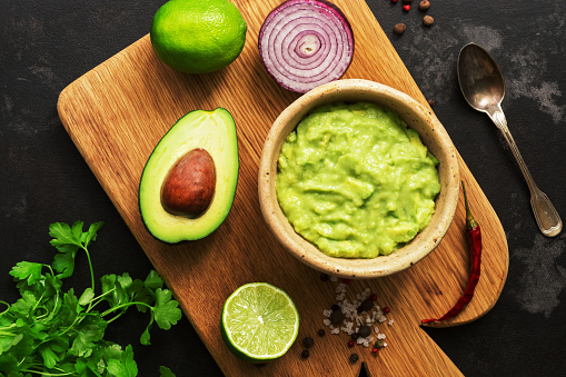 Guacamole and guacamole ingredients on cutting board,black marble background. Top view, copy space