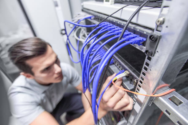 Man working in network server room Young man working in network server room with fiber optic hub for digital communications and internet cable network connection plug computer cable internet stock pictures, royalty-free photos & images