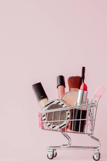 istock Creative concept with shopping trolley with makeup on a pink background. Perfume, sponge, brush, mascara, pencil, nail file, eye shadow, lip gloss in the basket, copy space 1139491130