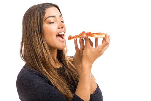 Closeup of female hipster enjoying tasty mouth watering pizza in white studio