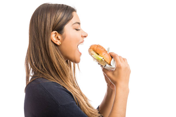 I Live To Eat Side view of attractive woman following unhealthful diet on white background mouth open stock pictures, royalty-free photos & images