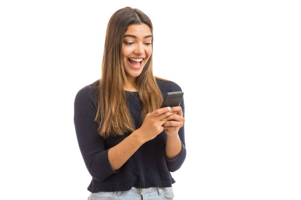 Oh Yeah! I Won The Lottery Excited beautiful woman receiving SMS in mobile phone over plain background surprised woman stock pictures, royalty-free photos & images