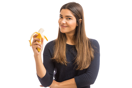 Portrait of attractive young woman in casuals having fiber rich fruit over white background