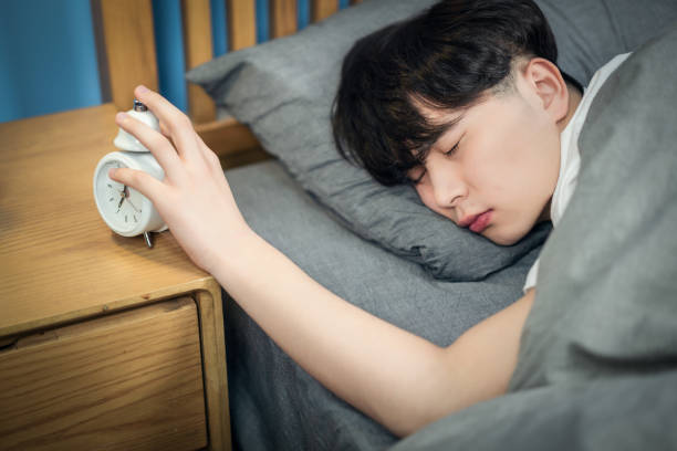 ベッドの上で眠っている若い男 - 起きれない ストックフォトと画像